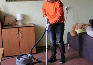 Uczeń odkurza podlogę.
