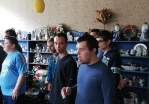 Zdjęcie przedstawia uczniów na tle wyrobów ceramicznych