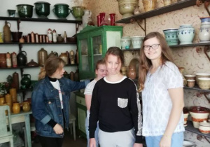Zdjęcie przedstawia uczniów na tle wyrobów ceramicznych