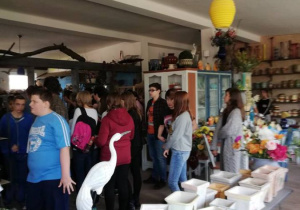 Zdjęcie przedstawia uczniów na tle wyrobów ceramicznych