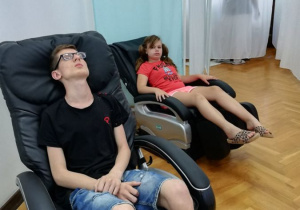 Uczestnicy Turnusu rehabilitacyjnego siedzą na fotelach masujących.