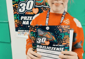 Zdjęcie przedstawia uczennicę trzymającą rozliczenie