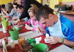 Zdjęcie przedstawia uczniów malujących wyroby ceramiczne