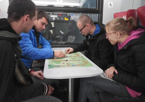 Uczniowie uczestniczący w grze planszowej podczas podróży pociągiem pociągu