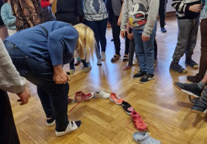 grupa uczniów bierze udział we wróżbie andrzejkowej z butami