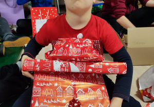Chłopiec ze swoimi zapakowanymi prezentami.