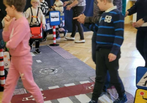 Uczniowie i nauczyciele poruszaja sie po makiecie ulic i przejść dla pieszych