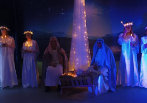 Maryja i Józef z aniołami wokół żłóbka trzymający świece..