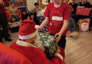 Chłopiec odbiera prezent od Mikołaja.