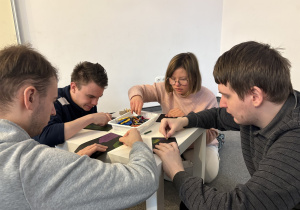 Uczniowie wykonują obrazki siedząc przy stolikach.