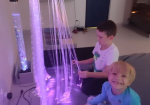 Dziewczynka i chłopiec bawią się światłowodami w sali doświadczania świata.