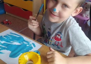 Chłopiec maluje niebieską farbą.