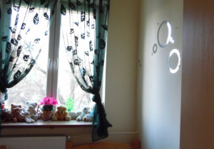 Zdjęcie przedstawia sypialnię w internacie. Na zdjęciu widać szafę i łóżko przykryte ładnym kocem.W oknie wiszą kolorowe firanki.